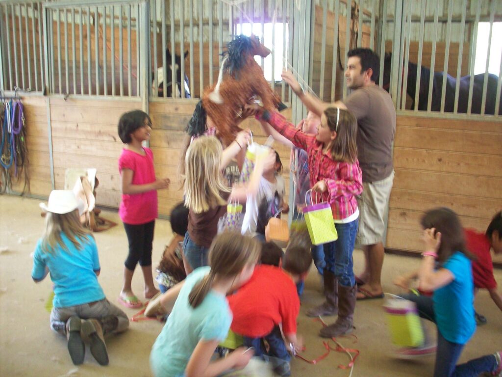 A group of children and adults playing with horses.