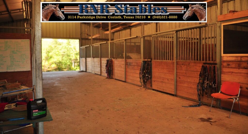 A stable with several stalls and ropes in it.